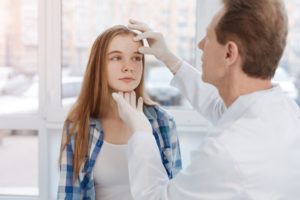 Dermatologist examining a patient's face