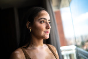 a young woman with vitiligo smiling as she looks out of a window.