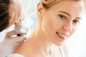 dermatologist examining neck with dermatoscope to identify skin type of patient