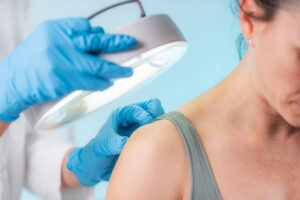 A dermatologist working in a dermatology clinic is examining a patient's skin for rashes and eczema.