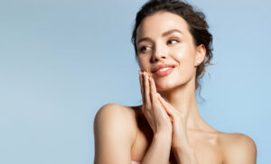 A woman with her hands near her face in joy from her cosmetic dermatology.